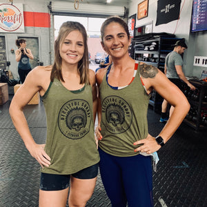 Two female CrossFit athletes wearing Deceitful Strength Indian skull Fitness Tribe tank tops in olive and black colors.